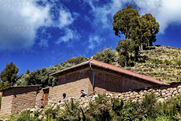 Rustic farm houses with two people and trees under a blue sky full of clouds, the countryside and