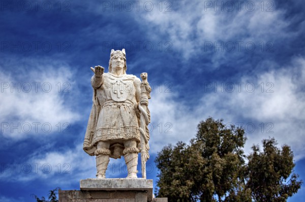 Stone statue of a warrior against a cloudy, blue sky, Great Inca monument on Taquile Island in Lake