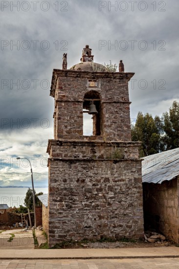 An old stone bell tower in cloudy sky surrounded by rustic landscape, The historic church on