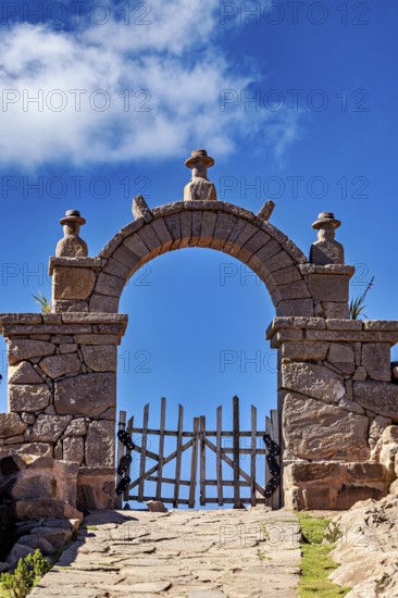 Stone gate under blue sky with some clouds, rustic appearance, stone gates on the island of Taquile