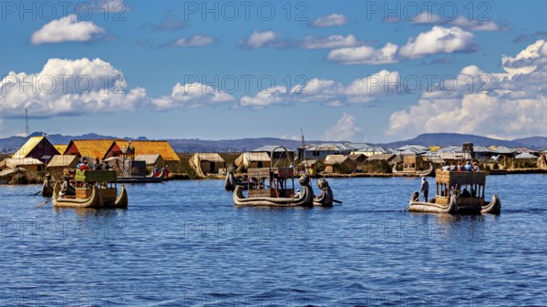 Several boats near a collection of reed huts on the lake, The floating reed islands of the Uros in