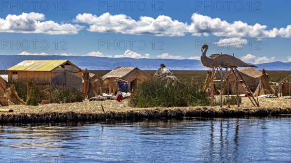 Handmade huts with thatched roofs and boats on the edge of a lake under a cloudy sky, The floating