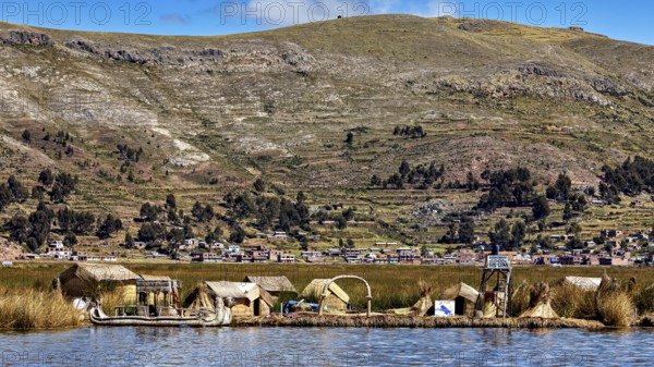 Small reed village on the shore with mountains in the background under a blue sky, The floating