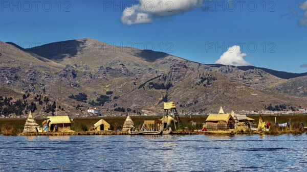 Small reed settlement on a lake against a mountain backdrop under a cloudy sky, The floating reed