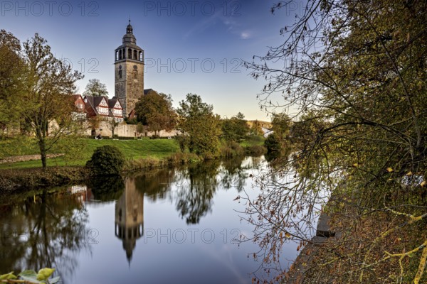 Church on the river, surrounded by autumnal trees with beautiful reflections in calm water, The