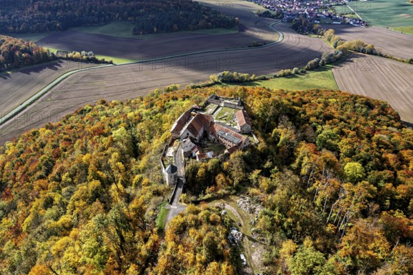 Aerial view of a castle on a hill surrounded by autumnal forest with colorful trees, Gleichenstein