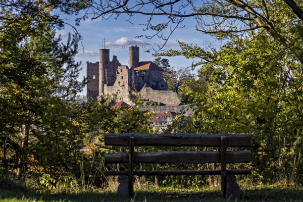 Bench in the foreground, medieval castle surrounded by trees, autumnal atmosphere, Hanstein Castle