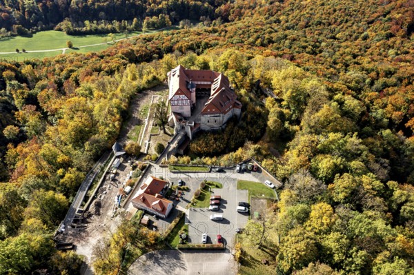 Castle taken from the air in the midst of autumn nature, with adjacent parking facilities,
