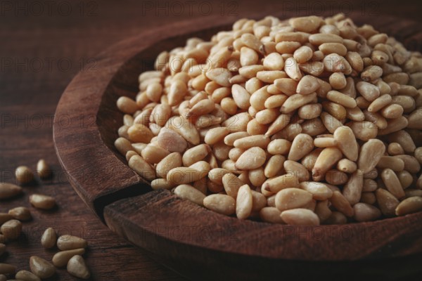 Peeled pine nuts, in a wooden bowl, on a wooden table, close-up, no people