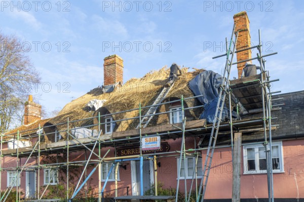 Thatcher at work replacing thatch ridge of thatched country pub building, Sorrel Horse, Shottisham,