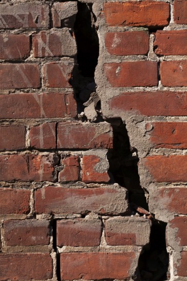 Close-up of large and deep wide open crack on exterior wall of red brick building, Quebec, Canada