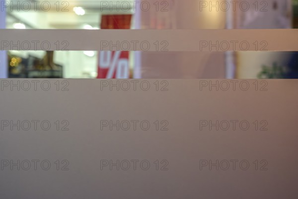 Symbolic picture of final sale: A percentage sign visible through the shop windows of a retail