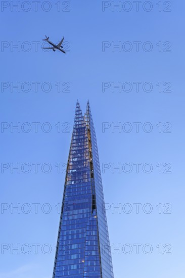 Airplane of British Airways flying over The Shard, skyscraper and tallest building in the United