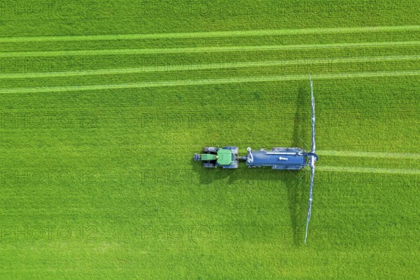 Aerial view over tractor towed liquid manure spreader, slurry spreader enabling the fertilization