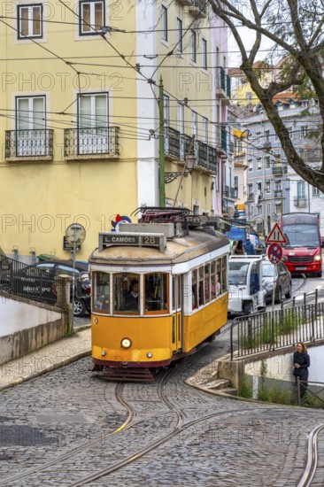Traditional vintage yellow tram on tram line 28 climbing steep cobbled street in the capital city
