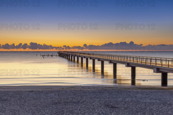 Seebrücke / pier and sandy beach at seaside resort Scharbeutz along the Baltic Sea at sunrise,