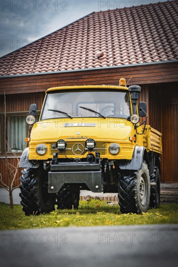 Yellow Unimog with four-wheel drive on a lawn in front of a wooden house, tree work, Gechingen,