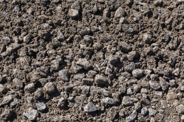 Close-up of sand mixed with grey crushed stone aggregate used to form a bed for constructing roads