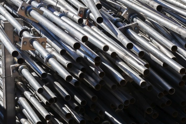 Close-up of stacked heavy duty galvanized steel poles in outdoor storage yard in early autumn,