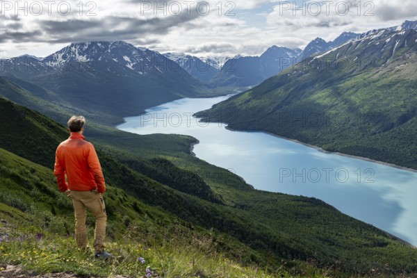 Mountaineer enjoys views of blue lake and mountains on Twin Peaks Trail, Eklutna Lake, Chugach