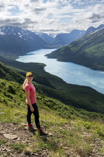Female mountaineer enjoying views of blue lake and mountains on Twin Peaks Trail, Eklutna Lake,