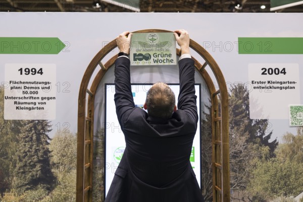 A stand operator hangs up a sign Congratulations to Messe Berlin on 100 years of Green Week at the
