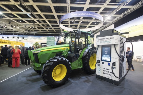 The prototype of an electric John Deere E-Power tractor is standing next to a charging station