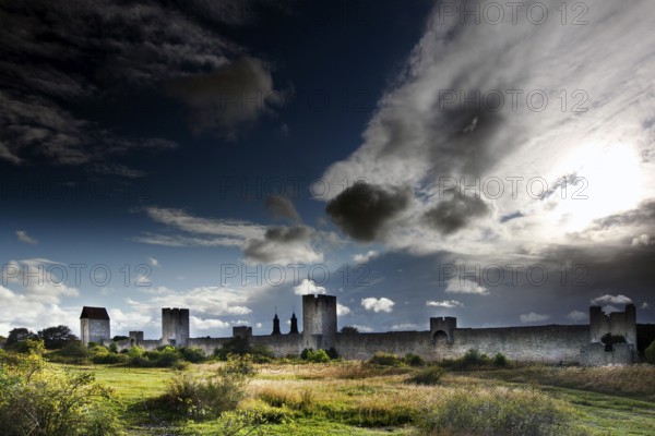 Impressive city wall of Visby with towers, under an imposing sky with dramatic clouds, Visby,