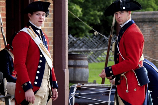 Two soldiers in red historic uniforms stand in front of a building and look alert, Williamsburg,