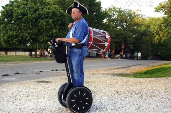 Man in period clothing rides on Segway and carries a drum, a rare sight, Williamsburg, Virginia,