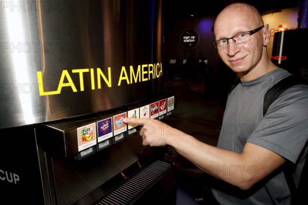 A man in the tasting room of the Coca-Cola Museum in Atlanta enthusiastically points to drinks from