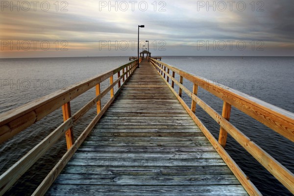 A long wooden pier stretches out into the calm sea at sunset in Biloxi, Biloxi, Mississippi, USA