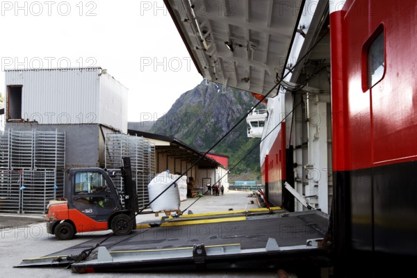 Hurtigruten ship in harbor with open cargo hatch with view of nearby mountainside, Øksfjord,