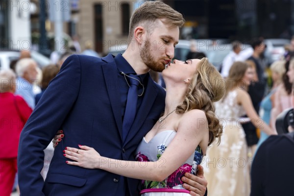 A young couple kisses during a high school graduation ceremony in a busy square, Vilnius, Vilnius