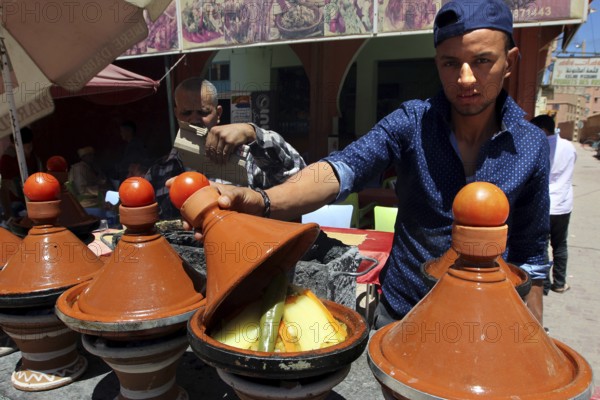 Traditional Moroccan cuisine with several brown tagine pots in a restaurant, El Kelâa m'Gouna,