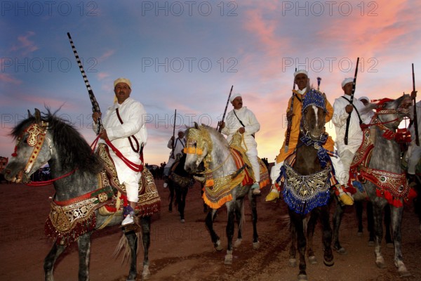 Riders wearing traditional clothes at sunset during a Fantasia performance, El Kelâa m'Gouna,