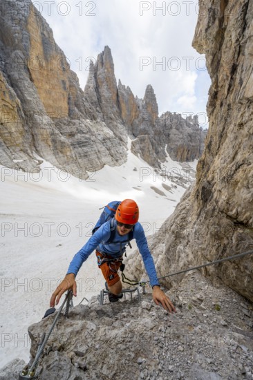 Mountaineer climbs on a steep rock face in the Via Ferrata dell'Ideale via ferrata, spectacular