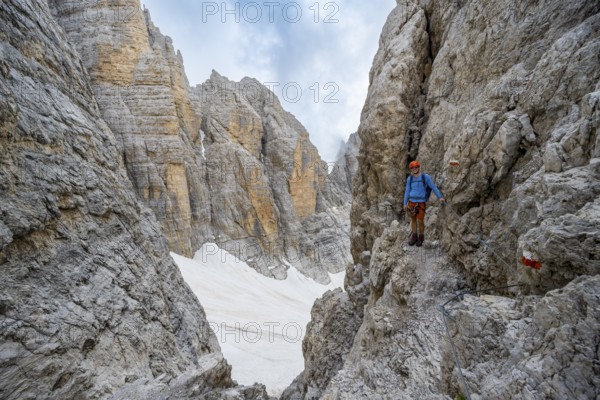 Mountaineer climbs on a steep rock face in the Via Ferrata dell'Ideale via ferrata, spectacular