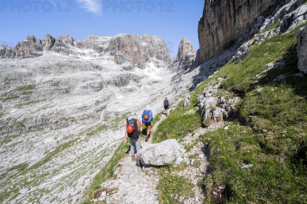 Three mountaineers on a hiking trail to Sella della Tosa, mountainous landscape in the Brenta