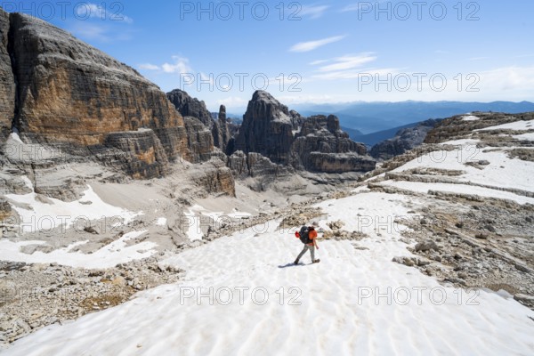 Mountaineers in a snowfield on the Sella della Tosa, mountain landscape with steep cliffs, Brenta