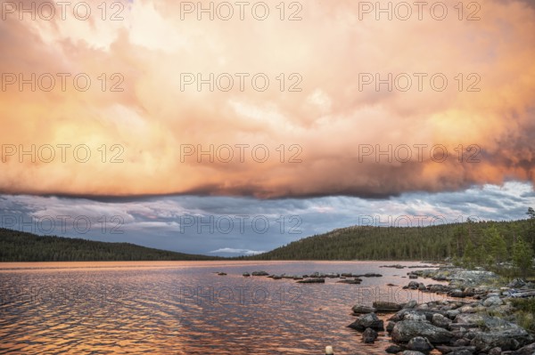 Evening cloud formation over Lake Gutulsjön illuminated by orange light, Gutulia National Park,