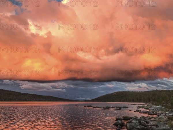 Impressive sky with intense colors reflected in the calm lake, Gutulia National Park, Drevsjö,