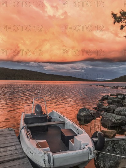 Boat moored on a jetty under a dramatic, colorful sky, Gutulia National Park, Engerdal, Innlandet,