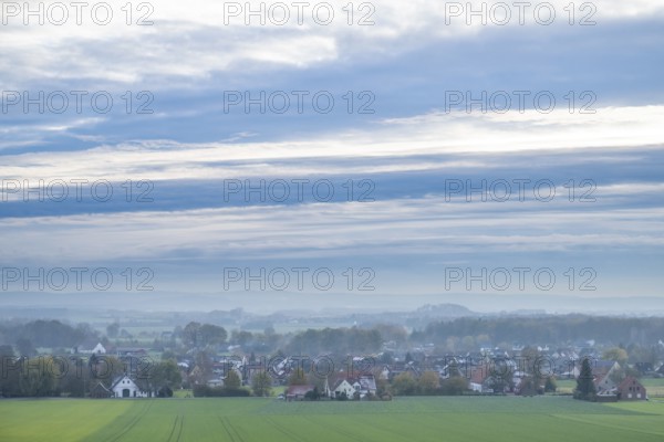 Extensive landscape with a village, fields, houses and cloudy sky in the morning,