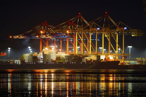 Industrial port at night with illuminated cranes and containers on the quay