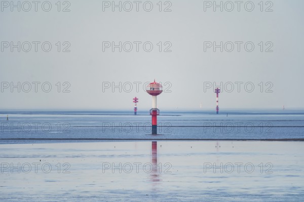 A red and white water buoy in the vast blue sea under a bright sky