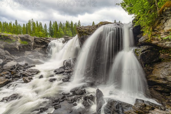 Mighty waterfall falling over rocky cliffs in a wooded area