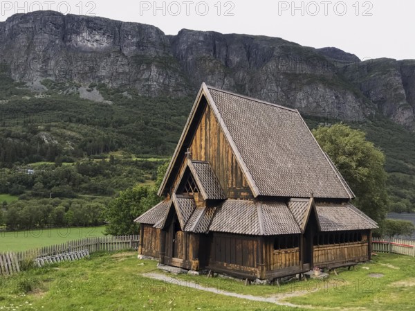 Øye, Innlandet, Norway, Traditional stave church in front of steep mountains in rural surroundings,
