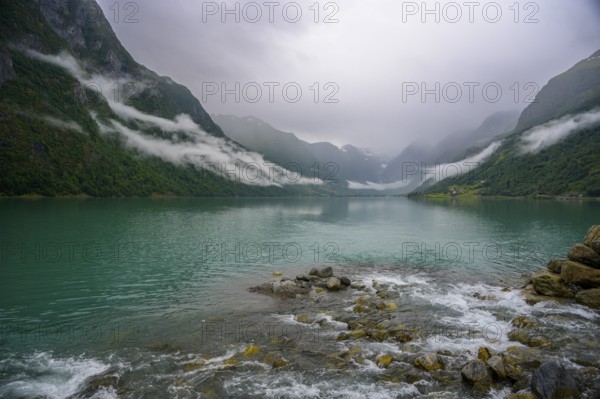 Olden, Vestland, Norway, Tranquil fjord landscape with mountains and cloudy sky, surrounded by