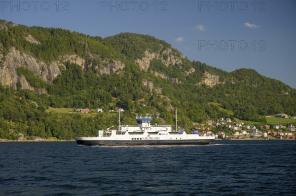 Hjelmeland, Rogaland Municipality, Norway, ferry on a fjord in front of a wooded landscape with